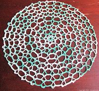 Full view of round green and white crochet doily
