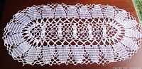 Full view of white oval crochet doily on table surface