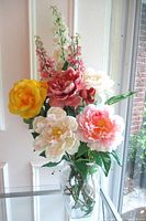 Front view of mixed faux flower arrangement in glass vase
