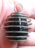 Side view of pendant showing wire cage coils around obsidian stone