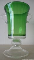 Front view showing emerald green body, clear stem and foot, both handles visible