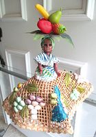 Full view of doll with wicker skirt and fruit accents