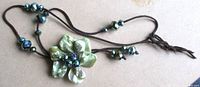 Full necklace showing flower pendant and cord with spaced beads