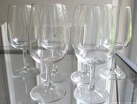 Six clear wine glasses standing on reflective surface