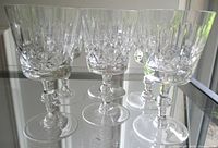 six crystal wine glasses grouped on glass shelf