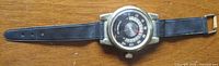Full view of watch-shaped thermometer with strap