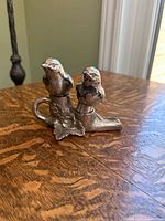 front view of two bird shakers seated on branch stand