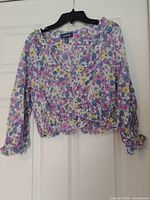 Front view of floral blouse on hanger