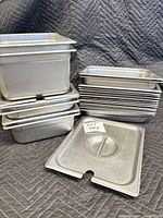 Stack of various depth stainless steam table pans and lids