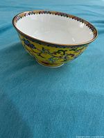 Side view of yellow porcelain bowl showing exterior floral scroll design