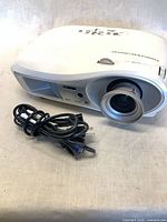 Front/side view of projector with lens cap off and cables beside