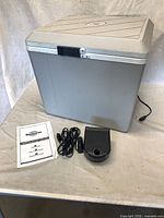 Closed Koolatron Voyager cooler with manual, AC adapter and 12 V cord