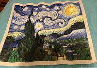 Full view of the hand-painted Starry Night canvas on blue surface
