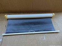 Projector screen partially extended showing housing, screen material, pull bar, mounting ends