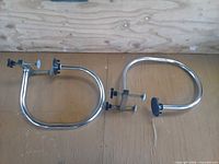 Two chrome clamp-on towel rings on wooden surface