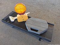 All four items arranged on creeper: socket set case, barricade light, squeegee