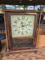 Front view of wooden mantel clock showing dial and lower glass panel
