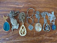 All seven necklaces laid out side by side on wooden surface