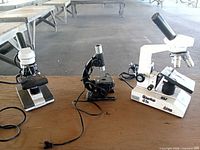Front view of three microscopes showing overall condition and attached cords