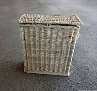 Front angle view of rectangular whitewashed wicker hamper with hinged lid closed