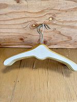 white wooden hanger with gold trim and swivel metal hook