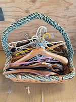 Wicker basket containing assorted wood and plastic hangers