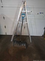 Aluminum step ladder with snow shovel in front