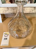 Full view of clear handblown glass decanter with medallion and size tag