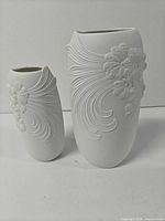 Front view of both Kaiser porcelain vases showing floral relief design and size difference