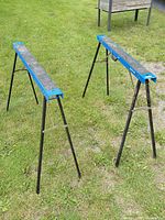 Two blue Mastercraft folding sawhorses standing on grass