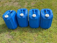Four blue water jugs front view on grass