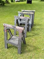 Four folding sawhorses lined up on grass
