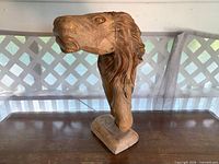 Left side view of carved wood lion bust on base