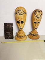 All three wooden masks side by side with tape for scale
