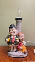 Front view of ceramic Laurel and Hardy lamp showing figures, column, bulb socket