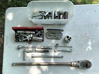 Entire lot laid out: plastic bin of sockets, red socket box, Mastercraft case, large ratchet handle, flex-head ratchet, extensions, adapter, spark plug socket