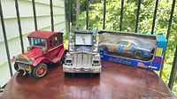 Group shot of all three items: red antique car, chrome truck clock, boxed #96 NASCAR die-cast