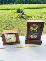 Both clocks side by side on table, tape measure for scale