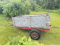 left side view of trailer showing plywood sides, red metal frame and single wheel