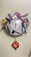 Front view of saw-blade wall clock with attached tools