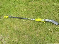 Full view of Sun Joe electric pole chain saw extended on grass