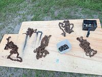 Overview of five chains, tri-ball hitch, bin of shackles on plywood