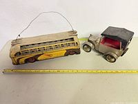 Overall view of bus and car with measuring tape for scale