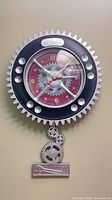 Full view of gear-shaped wall clock with pendulum