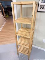 Front angled view of assembled pine shelving unit showing five slatted shelves