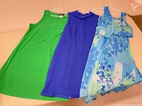 Three dresses laid side by side on hangers