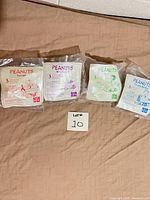 Front view of four sealed Peanuts Happy Meal toy bags