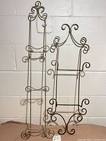Both metal wall plate hangers side by side showing height difference and scroll design
