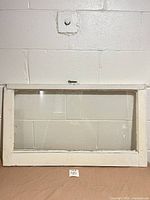 Front view of white wood window frame with glass and latch