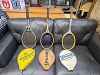 Three rackets lying on couch with their covers displayed